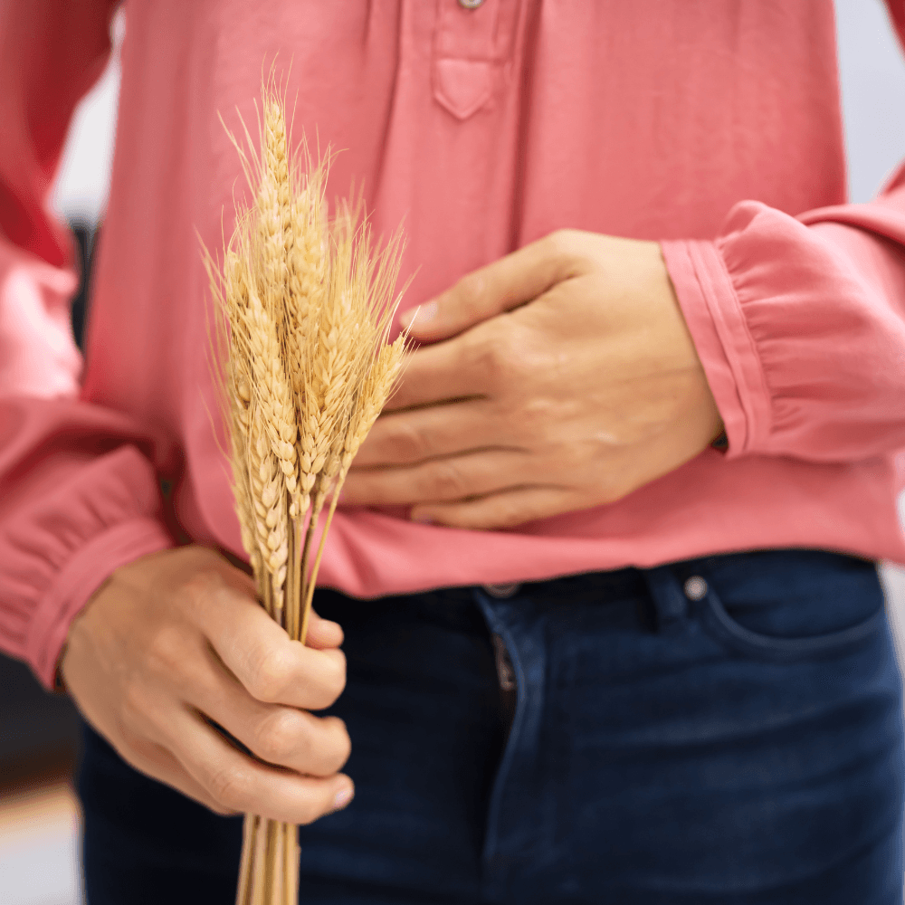 Eine Frau hält in der einen Hand Weizen und die andere Hand hält den Bauch