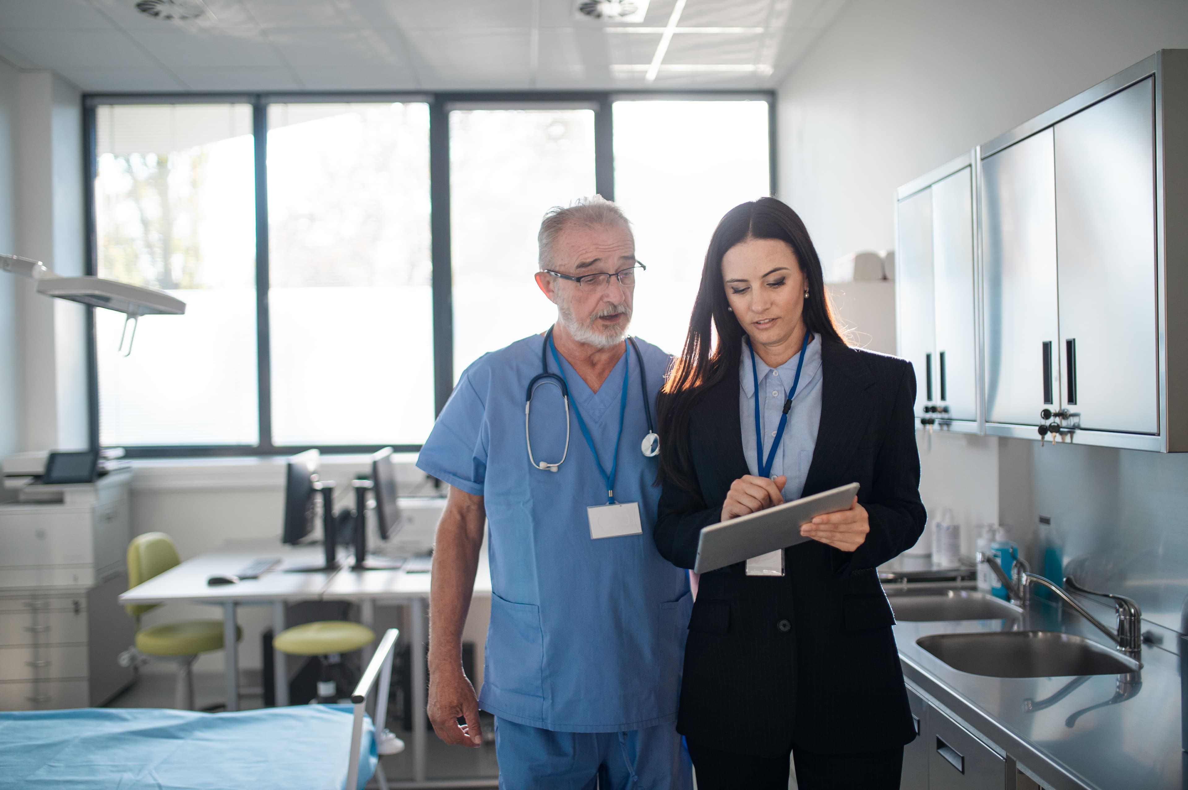 Qualitätsbeauftragte im Gespräch mit Pflegefachkraft in einem Krankenhauszimmer.