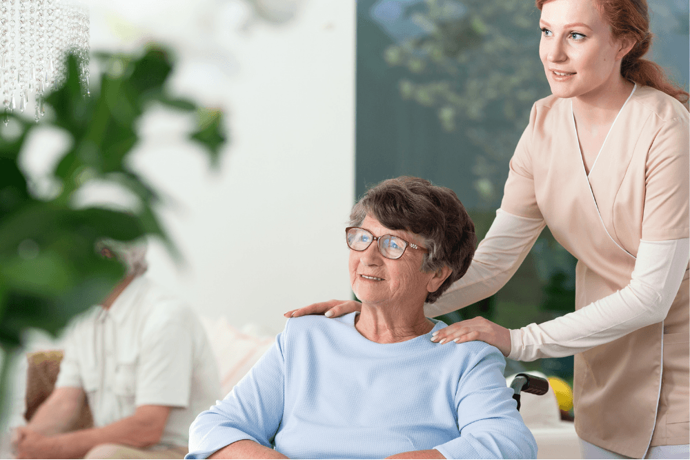 Eine Gerontofachkraft schiebt eine Patientin mit dem Rollstuhl